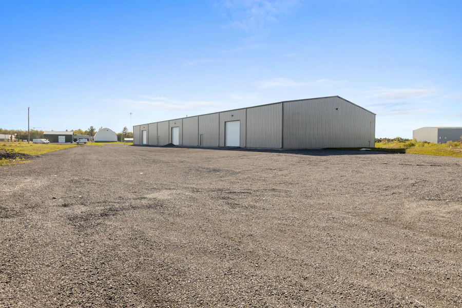 Long pre-engineered steel warehouse on a cleared industrial site under a blue sky