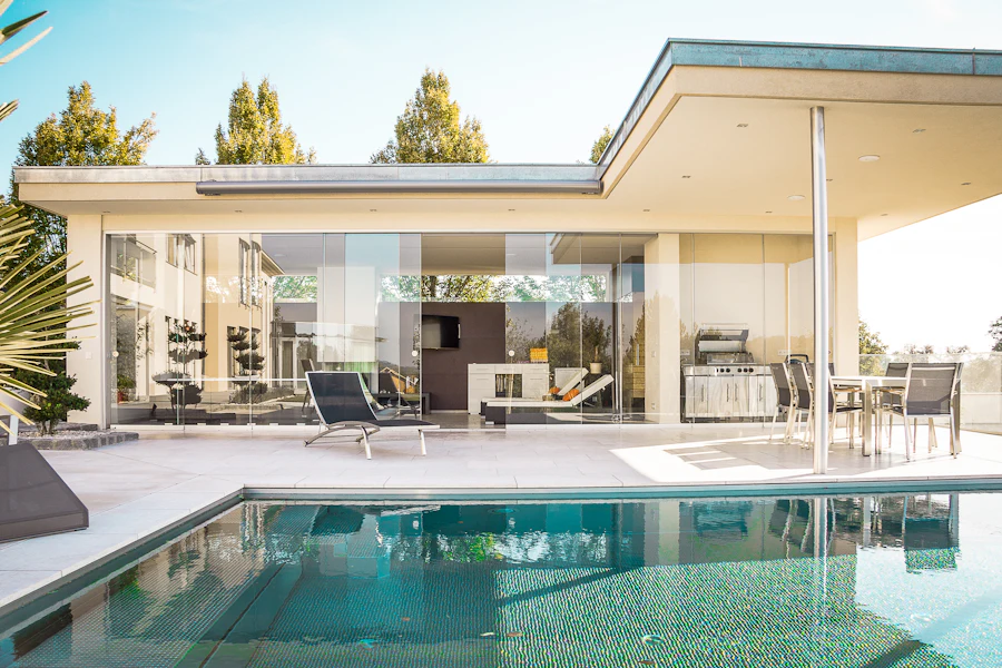Low modern pavilion with a deep roof overhang and glass walls opening onto a pool